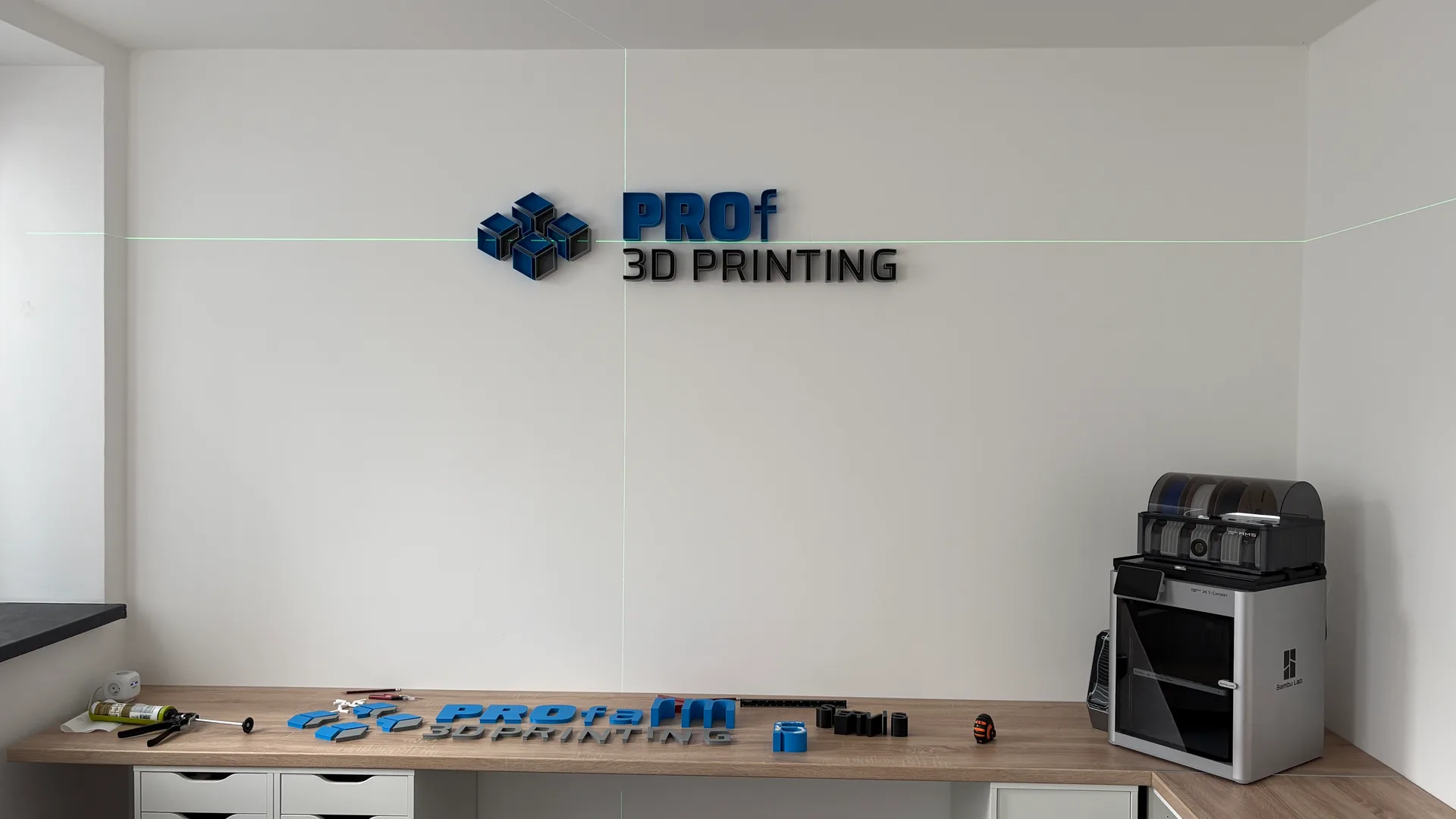 Mounting the logo on the wall using a laser level, the remaining letters laid out on the desk