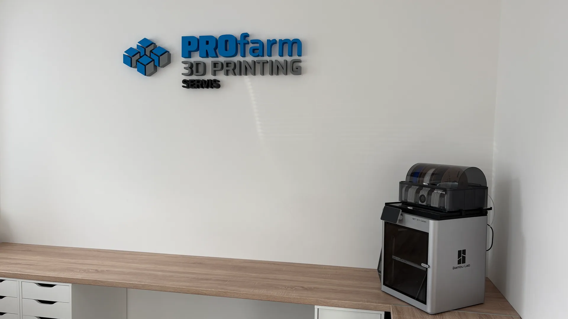 The finished PROfarm 3D PRINTING SERVIS logo on the wall above the workbench